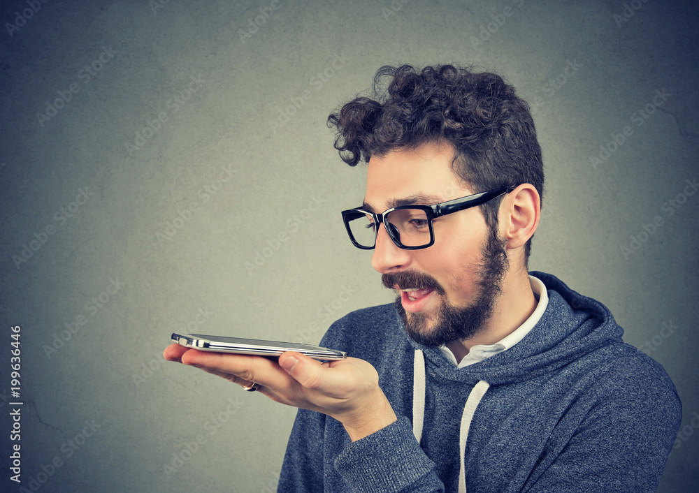 Naklejka premium Hipster man in glasses using a smart phone voice recognition function