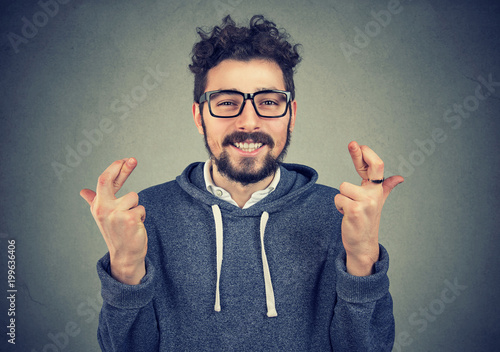 Bearded guy in blue hoodie crossing fingers