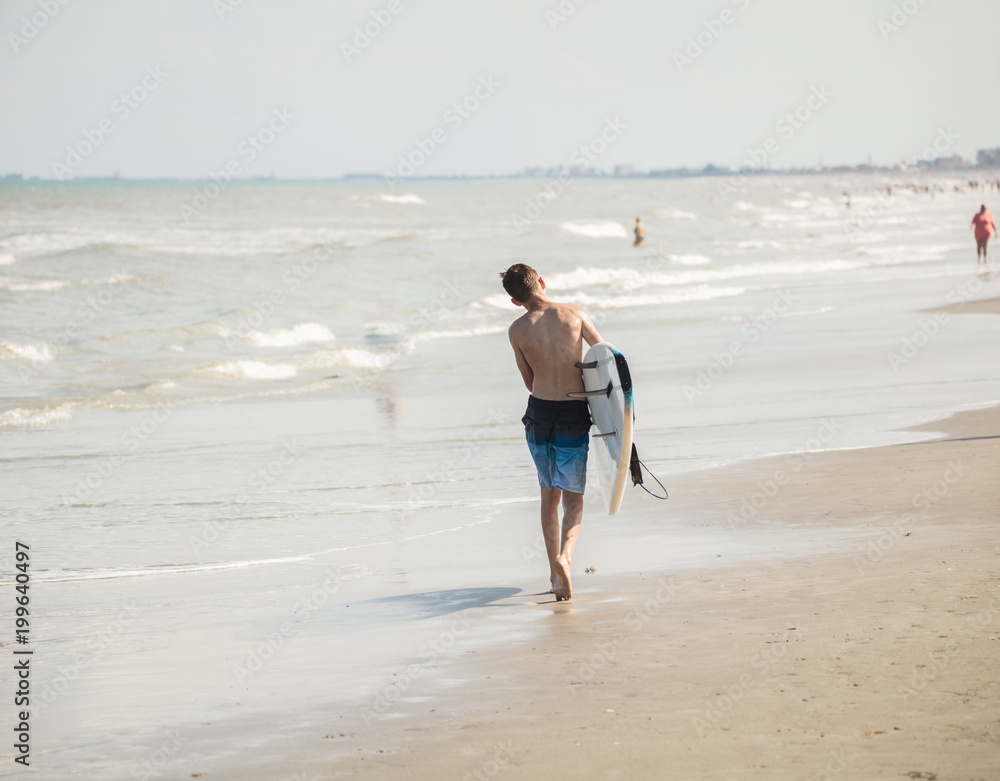 unknown surfer is heading back into the tides as the waves build unknown surfer is heading back into the tides as the waves build