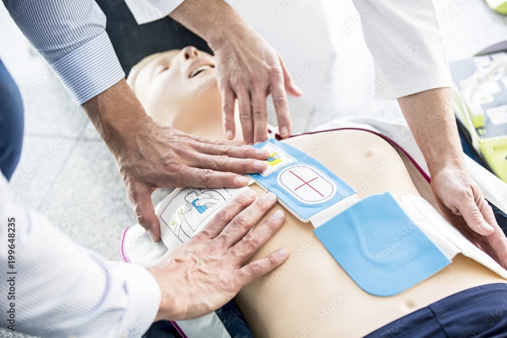 First-aider placing defibrillator pads First-aider placing defibrillator pads