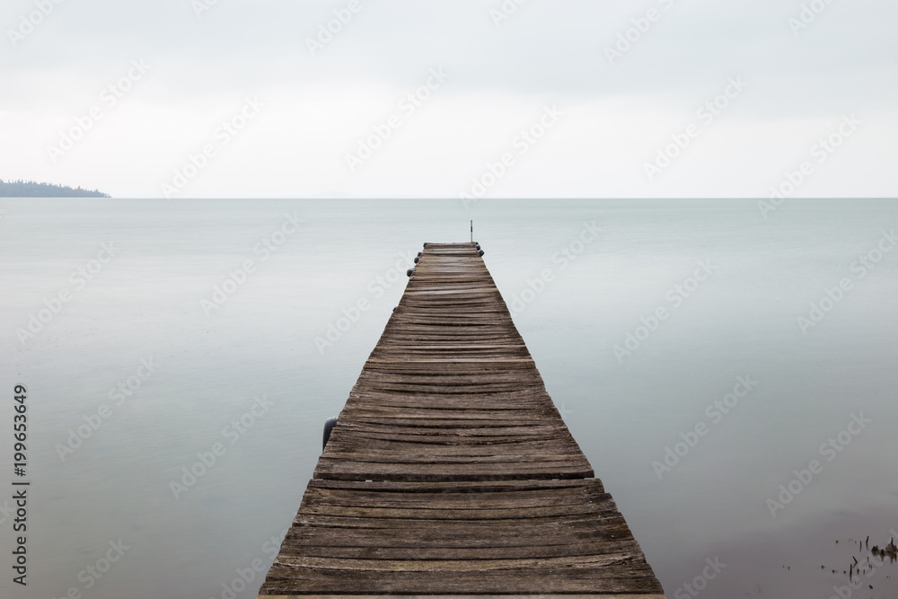 Long exposure first person view of a pier on Trasimeno lake (Umbria), with perfectly still water