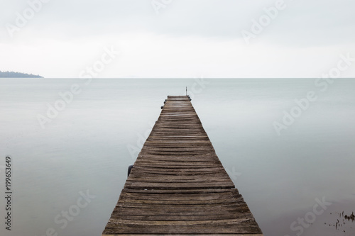 Long exposure first person view of a pier on Trasimeno lake (Umbria), with perfectly still water