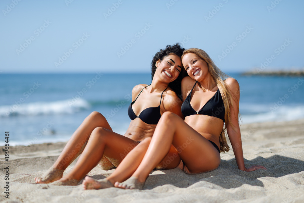 Two young women with beautiful bodies in swimwear on a tropical beach Two young women with beautiful bodies in swimwear on a tropical beach