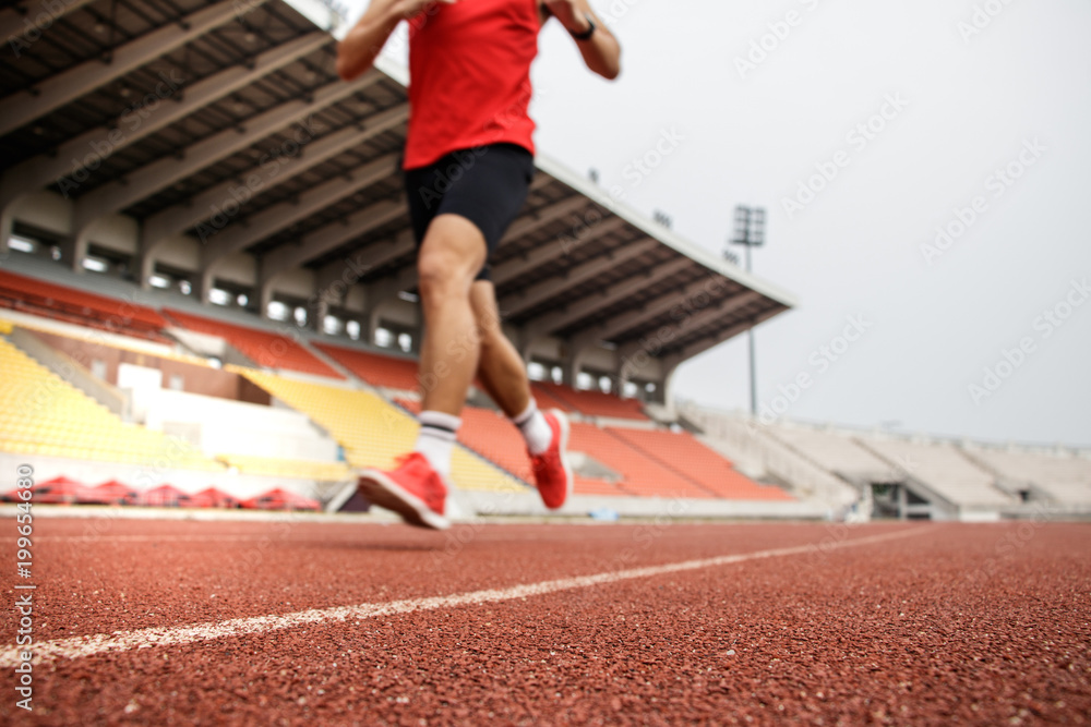 Sport Background. Runner. Athletic man running on stadium track. Selective focus.