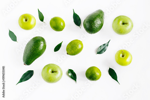 Green fruits avacado, apples, lime and leaves creative concept top view on the white background.