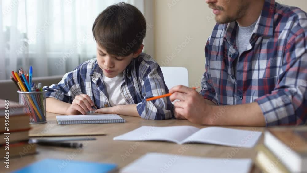 Father and son doing homework together, dad explaining task, school education Father and son doing homework together, dad explaining task, school education