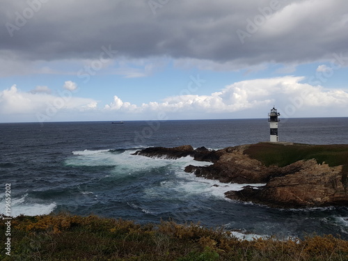 faro en las rocas con olas rompiendo en las rocas