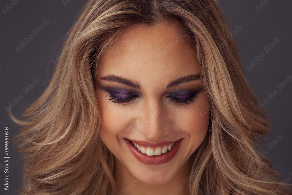 Lovely blonde woman smiling with eyes closed while wearing purple eyeshadow Lovely blonde woman smiling with eyes closed while wearing purple eyeshadow