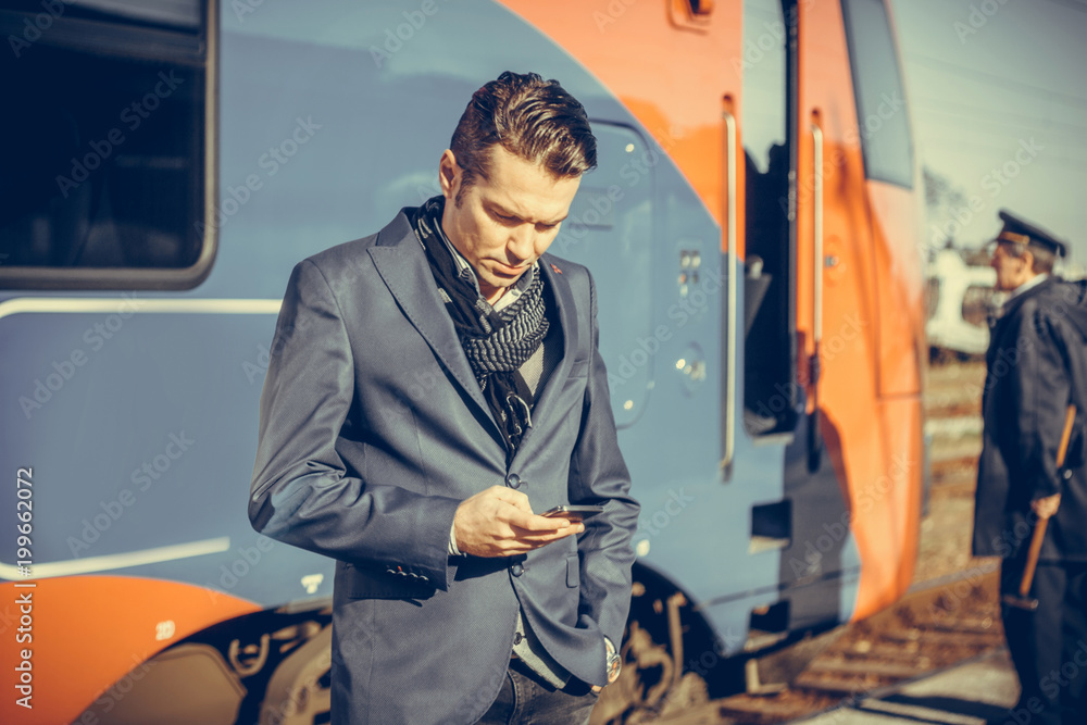 Businessman checking schedule on mobile phone at train station.