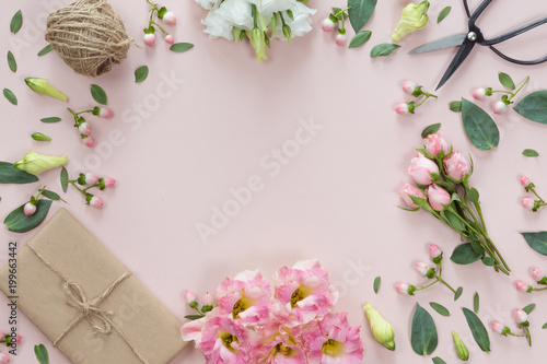 Flowers composition with gift on white pink background. Flat lay, top view.
