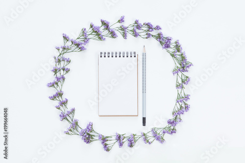 Top view of blank notebook with pencil in floral frame of flowers on whitedesk background, flat lay. photo