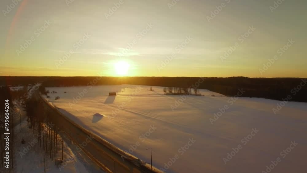 Snowy fields by a small highway during sunset Snowy fields by a small highway during sunset