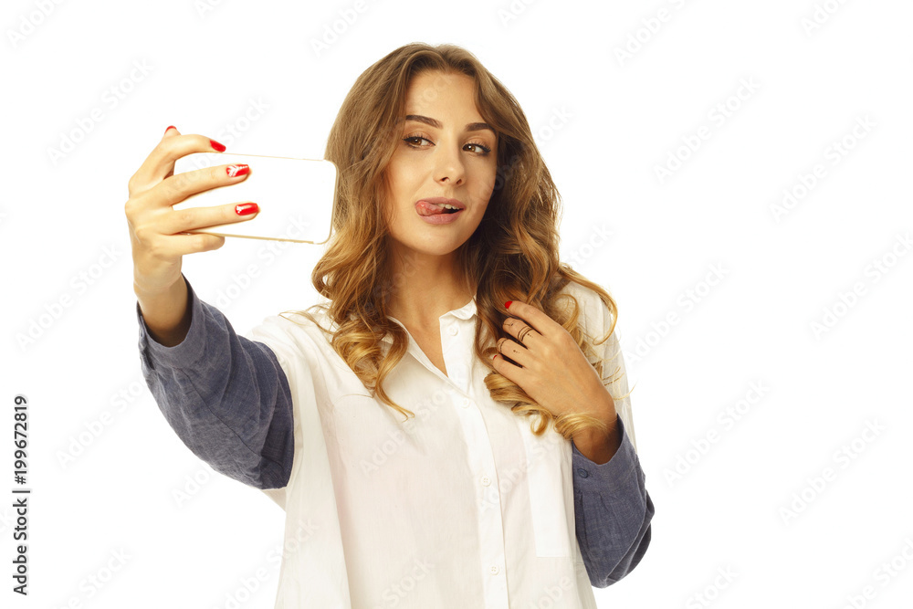 Portrait of a beautiful young woman making selfie on smart phone showing tongue. Happy woman photographing herself. Portrait of a beautiful young woman making selfie on smart phone showing tongue. Happy woman photographing herself.