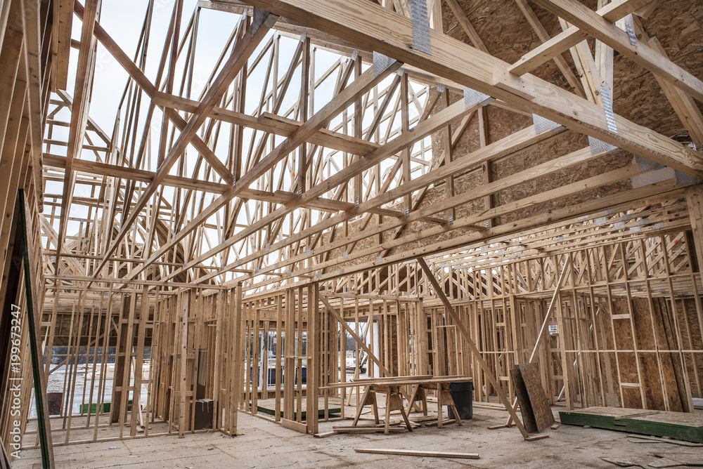 Interior of new home construction work site walls and roof trusses of wood 2x4's and waferboard and plywood flooring Interior of new home construction work site walls and roof trusses of wood 2x4's and waferboard and plywood flooring