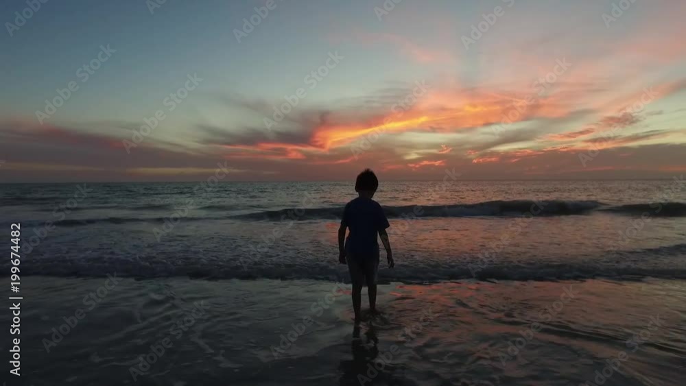 SILOUHETTE BOY WALKING INTO SUNSET OCEAN SILOUHETTE BOY WALKING INTO SUNSET OCEAN