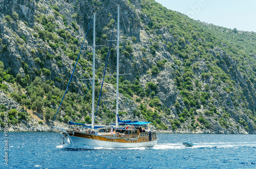 Wooden yacht float sails in Aegean sea Tyrkey near deserted island with clear blue water rocky mountains hiking journey bay photo