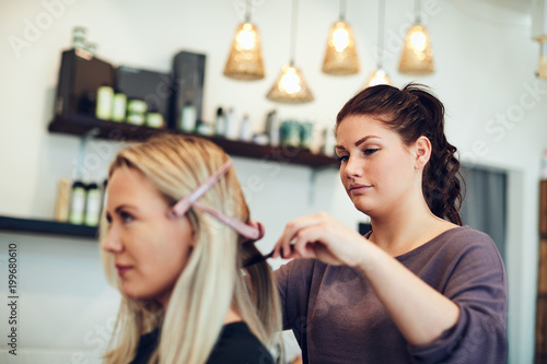 Young hairdresser styling a clients hair in her salon