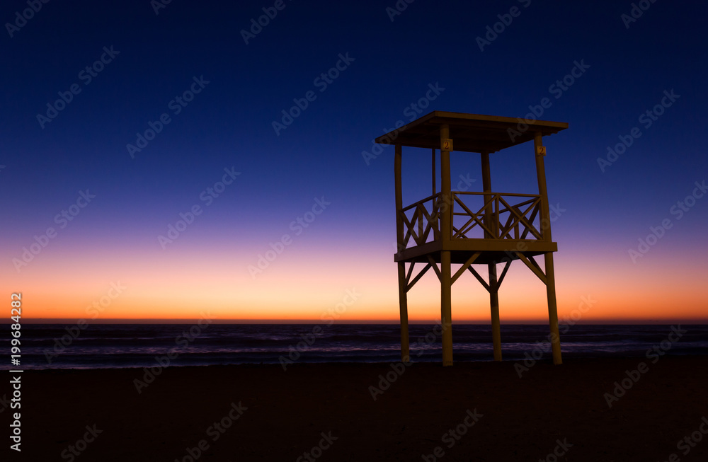 Lifeguard tower on empty beach at colorful sunset in La Serena, Chile. Nobody on calm, peaceful dusk by the sea