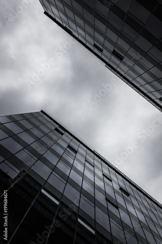 Modern glass and steel office buildings from below with cloudy sky in Santiago, Chile. Architecture design, angle perspective. Black and white photography