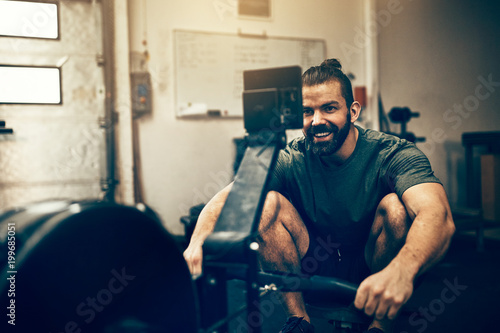 Young man exercising on a rowing machine at the gym