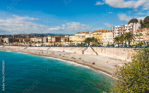 Bright turquoise sea, blue sky and old walls along beach and Promenade des Anglais in Nice, Cote d'Azur, France