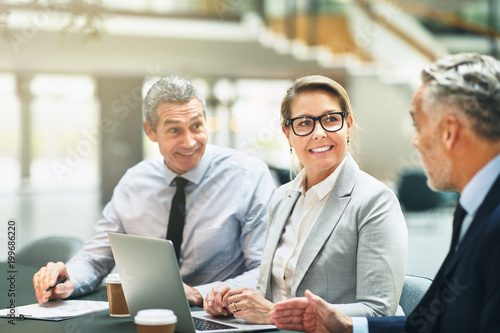 Mature office colleagues smiling and talking together during a m