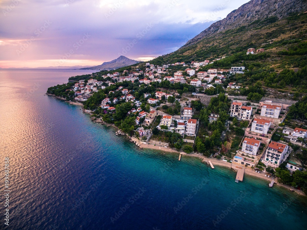 Aerial top view of a village located on a mountain by the sea at sunset in Croatia