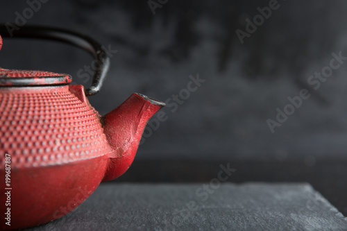 Red iron teapot on dark color background photo