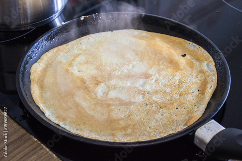 French crepe, thin pancake on a frying pan, cooking process close up