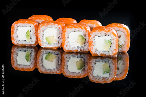 Delicious Philadelphia sushi rolls with rice, avocado, cream cheese and salmon on dark background