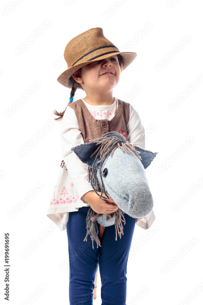 Cute little girl dressed like a cowboy playing with a homemade horse.