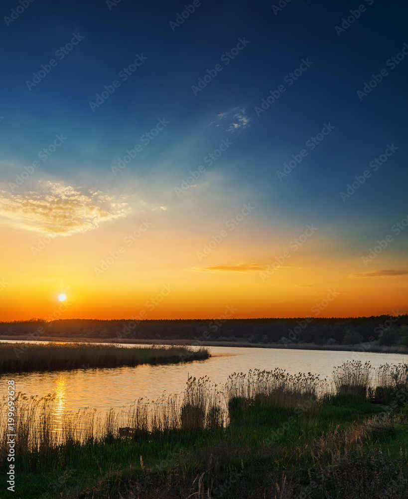 orange sunset in dark blue sky over river