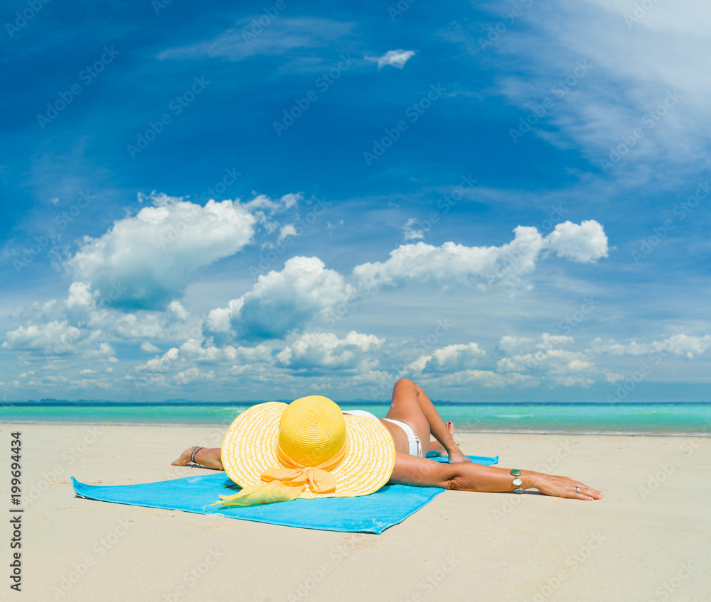 Woman in bikini wearing a yellow hat at tropical beach