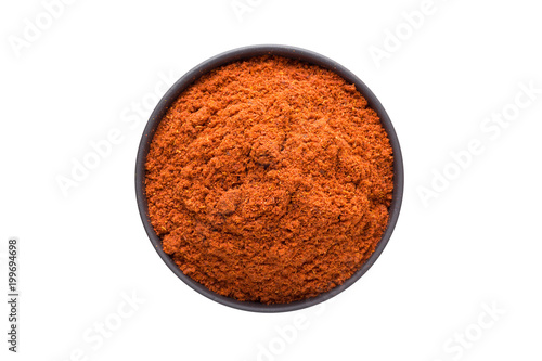 chili powder in clay bowl isolated on white background. Seasoning or spice top view