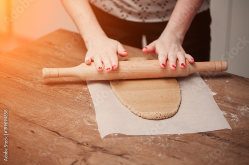 Hands rolling dough for gingerbread on the wooden table