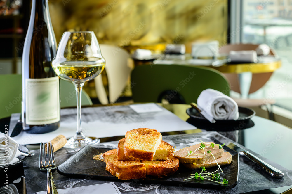 Tasty foie Gras with toasts and glass of white wine at a restaurant Tasty foie Gras with toasts and glass of white wine at a restaurant