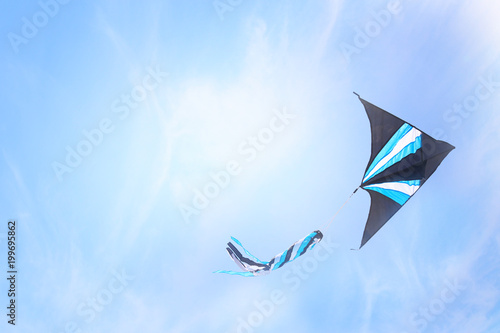 Fototapeta Naklejka Na Ścianę i Meble -  Colorful kite flying in the blue sky through the clouds