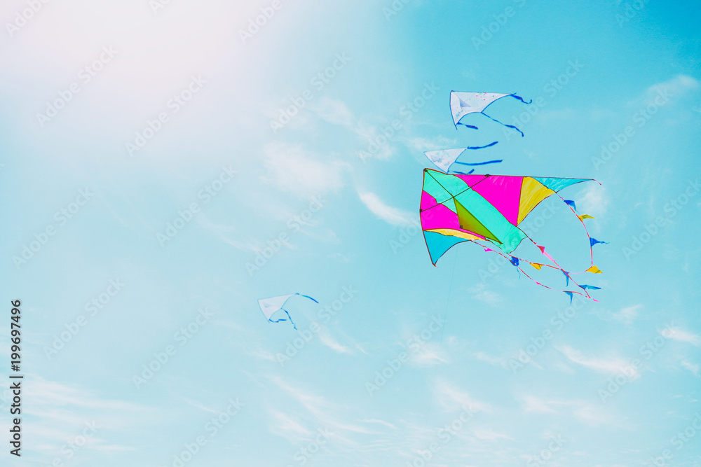 Colorful kite flying in the blue sky through the clouds Colorful kite flying in the blue sky through the clouds