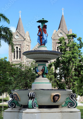 water fountain in park with church steeples in background, St. Kitts, Lesser Antillies, Caribbean photo