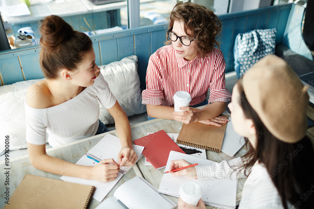 Group of contemporary businesswomen or students having meeting in cafe to discuss new ideas Group of contemporary businesswomen or students having meeting in cafe to discuss new ideas