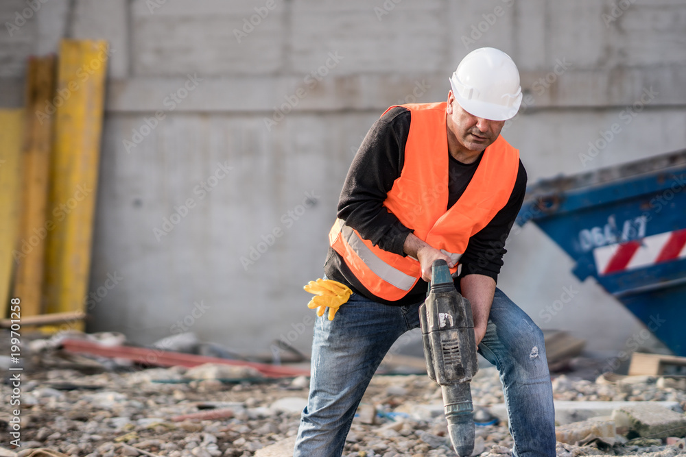 Male construction worker using a jackhammer on construction site Male construction worker using a jackhammer on construction site