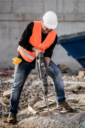 Male construction worker using a jackhammer on construction site