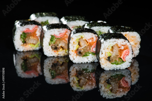 Traditional Japanese cuisine. Tasty sushi rolls with rice, cream cheese, salmon, cucumber and tuna on dark background