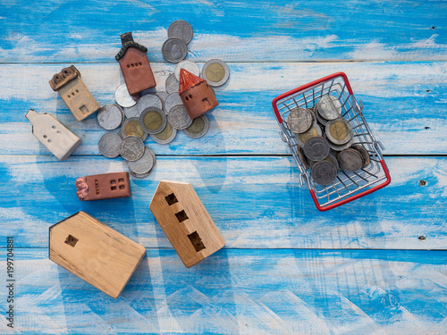 Small toy house and coins in basket on wood floor for savemoney and real estate concept photo