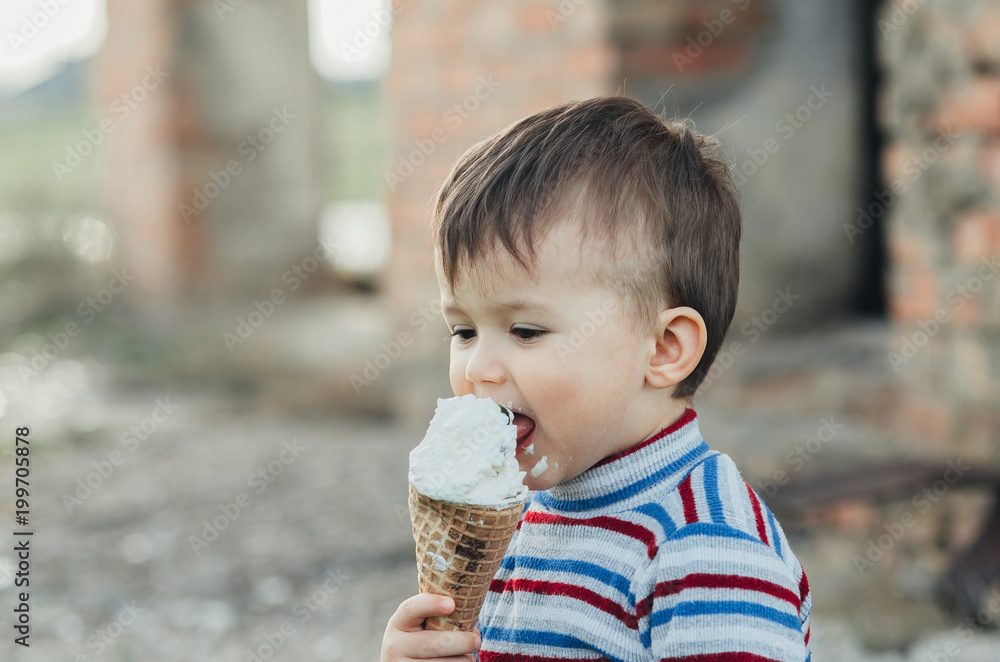 little cute boy eating ice cream three years very appetizing, amid nature, green grass little cute boy eating ice cream three years very appetizing, amid nature, green grass