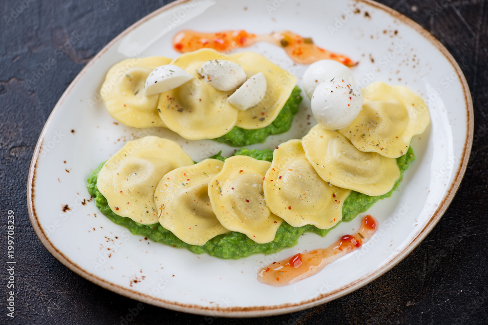 Ravioli with green peas puree and mozzarella on a plate, studio shot, selective focus Ravioli with green peas puree and mozzarella on a plate, studio shot, selective focus