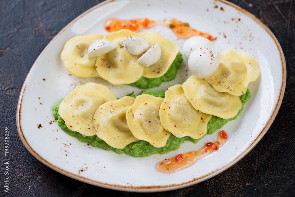 Ravioli with green peas puree and mozzarella on a plate, studio shot, selective focus