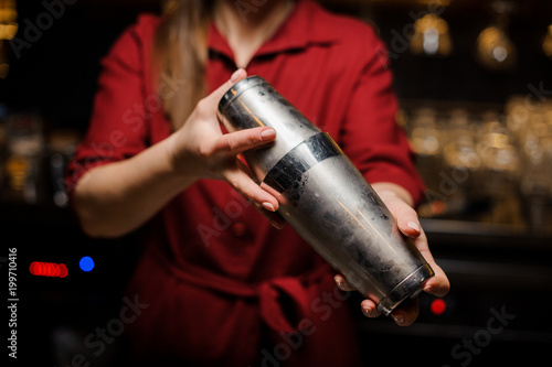 Female bartender making cocktail at the steel bar counter