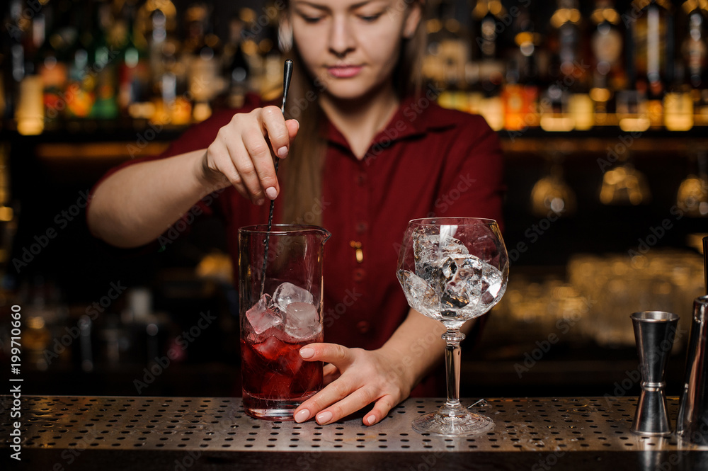 Bartender girl stiring a fresh delicious red cocktail