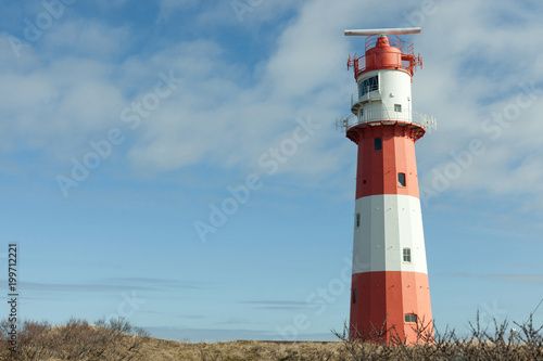 beautiful red and white lighthouse in nordic dune landscape